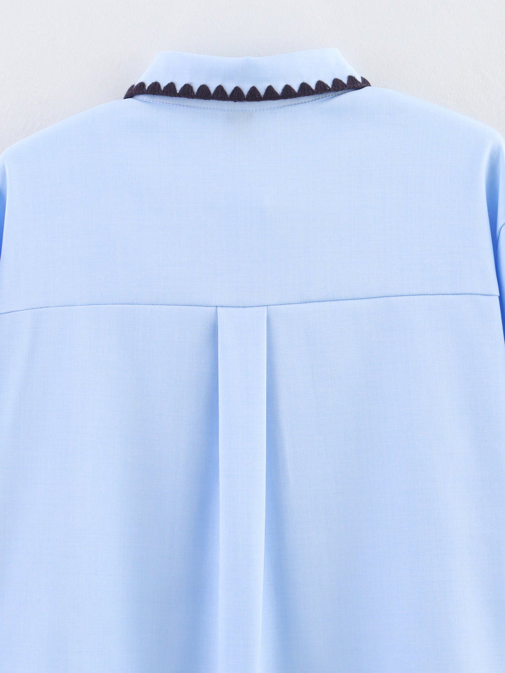 Chemise bleue à manches longues ample, style chic et automnal, inspirée par les coquillages.