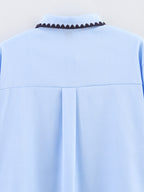 Chemise bleue à manches longues ample, style chic et automnal, inspirée par les coquillages.