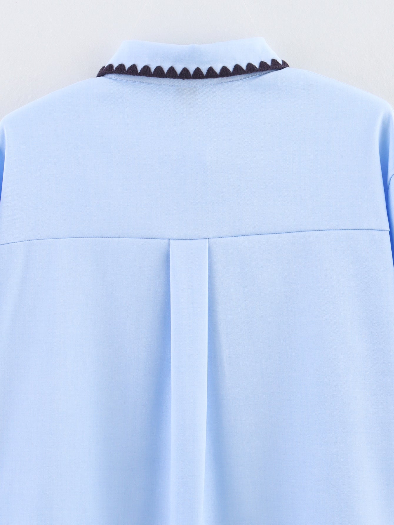 Chemise bleue à manches longues ample, style chic et automnal, inspirée par les coquillages.