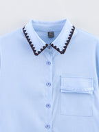 Chemise bleue à manches longues ample, style chic et automnal, inspirée par les coquillages.