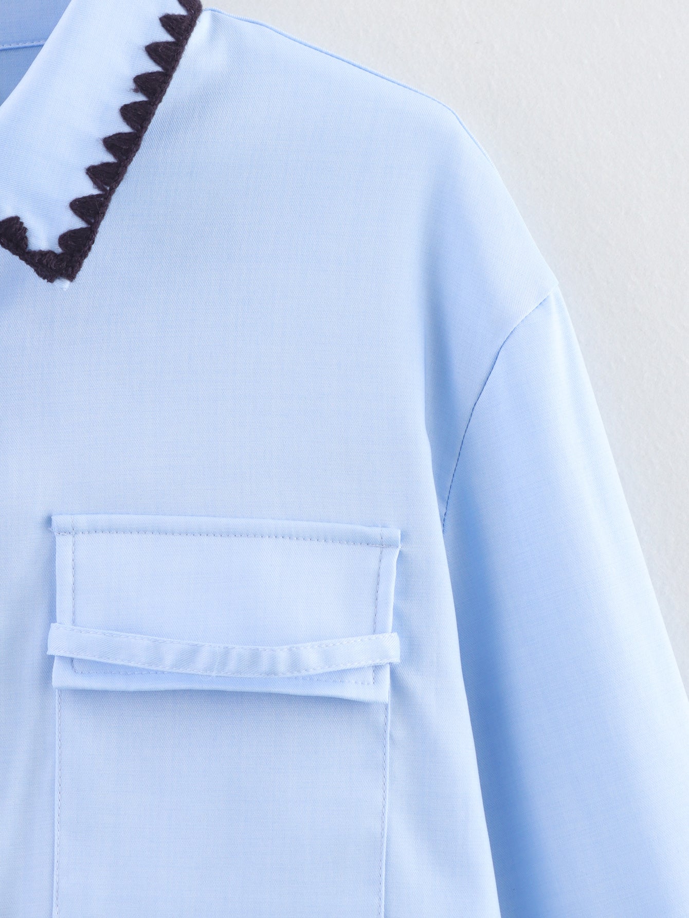 Chemise bleue à manches longues ample, style chic et automnal, inspirée par les coquillages.