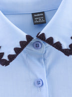 Chemise bleue à manches longues ample, style chic et automnal, inspirée par les coquillages.