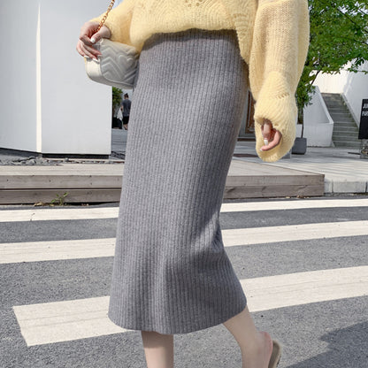 Jupe tricotée femme automne-hiver avec pull, taille haute, mi-longue, en laine épaisse fendue sur les hanches.